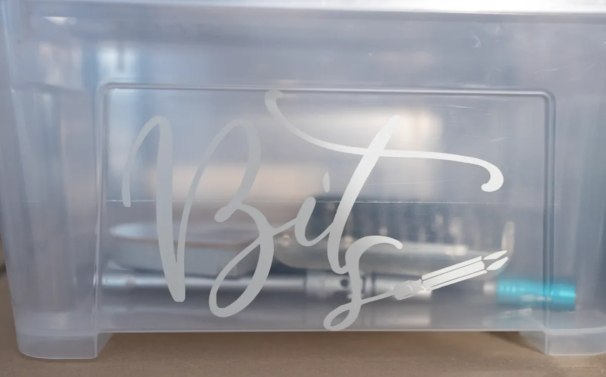 Durchsichtige Box mit dem Schriftzug Bits in schwungvoller Kalligrafie und einer kleinen Schraubendreher-Illustration, dahinter liegt das Bit-Set bereit.