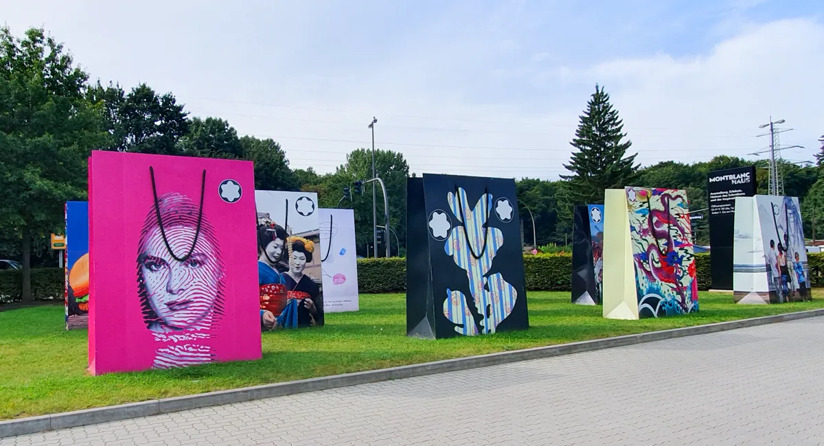 Überdimensionale Montblanc-Geschenktüten mit Kunstmotiven stehen wie Skulpturen auf der Wiese vor dem Montblanc Haus in Hamburg.