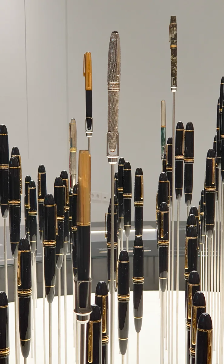 Über dem Feld schwarz-goldener Füllfederhalter erheben sich ein silbern glänzender Füller mit Gitterstruktur, ein gesprenkeltes und ein marmoriertes Modell.